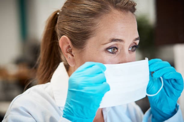 Forensic Nurse Putting On Face Mask